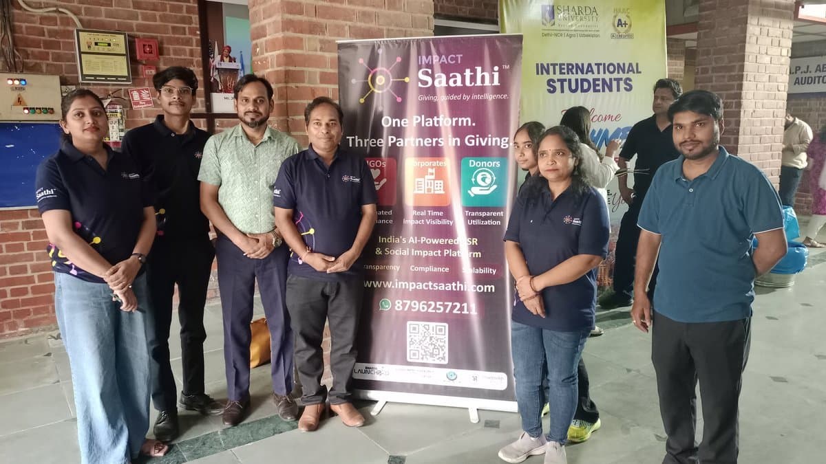 Impact Saathi team members with rollup banner outside venue